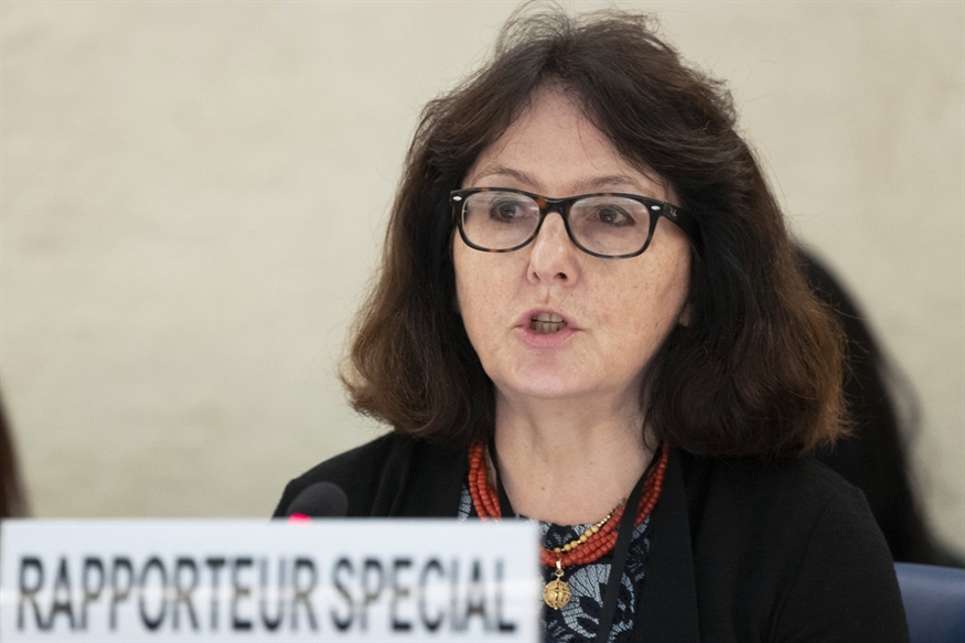 [ai] A woman with dark hair and glasses speaking at a conference, with a sign that reads 'RAPPORTEUR SPECIAL' in front of her.